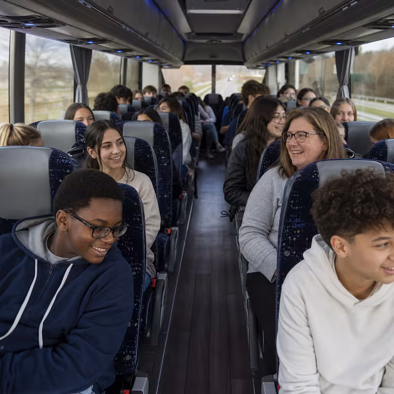 Group boarding a white charter bus for School Transportation transportation in Indianapolis